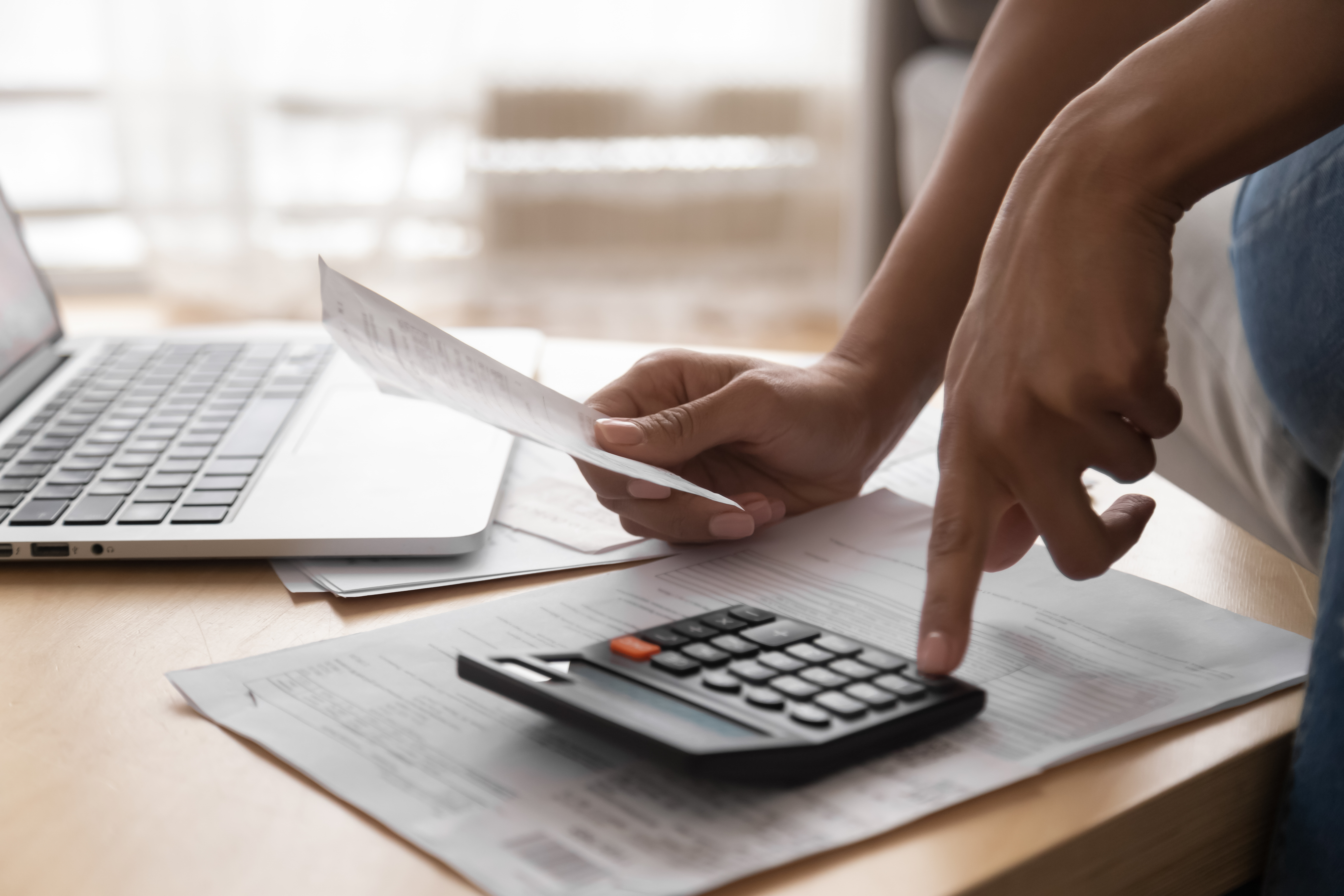 Woman Holding Paper Bills Using Calculator